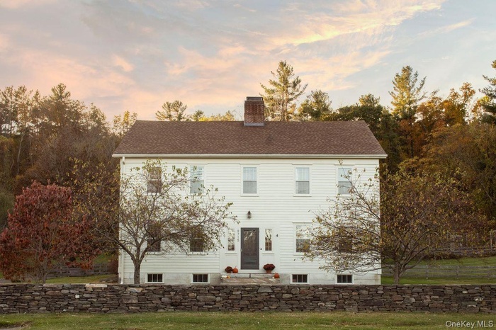 View of front facade with a chimney, a front yard, and roof with shingles