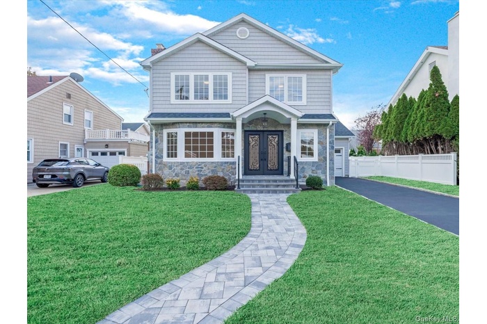 View of front of home featuring stone siding, a chimney, driveway, and a garage