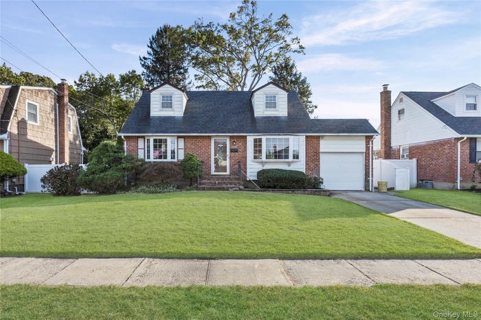 Cape cod house with brick siding, driveway, a garage, and a shingled roof