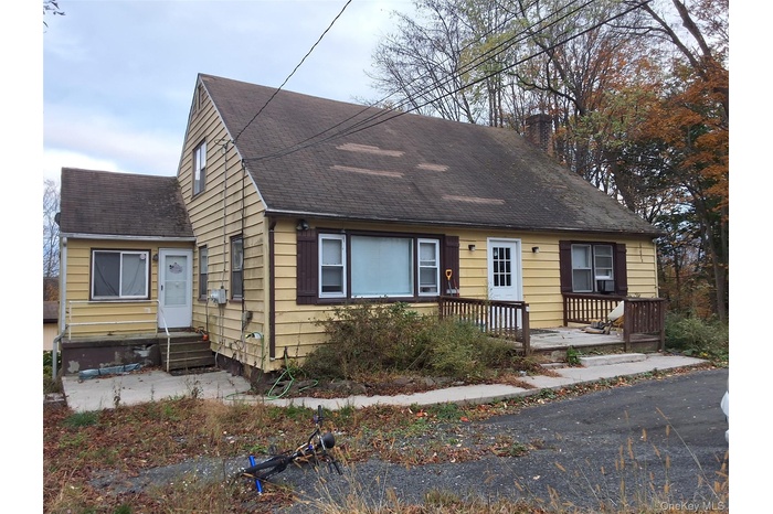 Cape cod-style house featuring roof with shingles and a chimney