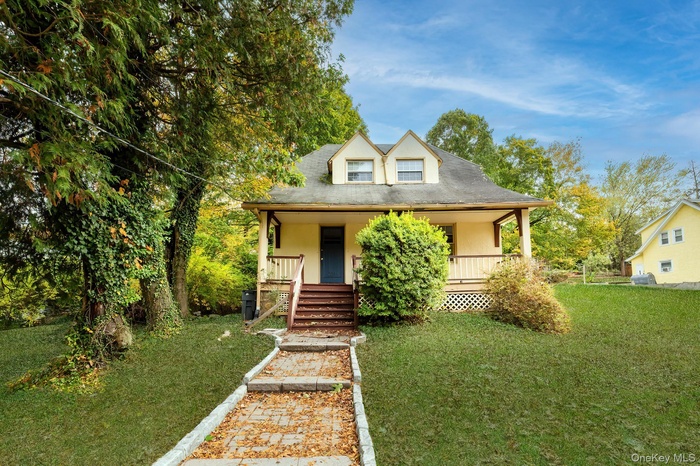 View of front of house with covered porch, a front lawn, and stucco siding
