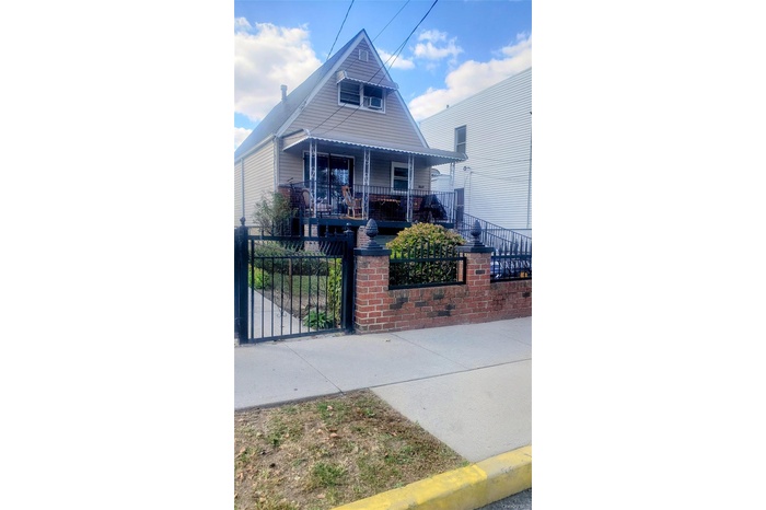 View of front of property with a fenced front yard, a porch, and a gate