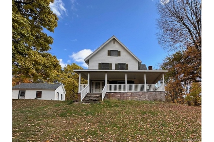 Farmhouse-style home featuring a porch and a front lawn