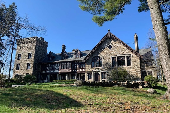 Back of property with stone siding, a lawn, and a chimney