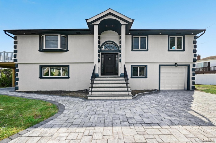 View of front of home with stucco siding, decorative driveway, and an attached garage