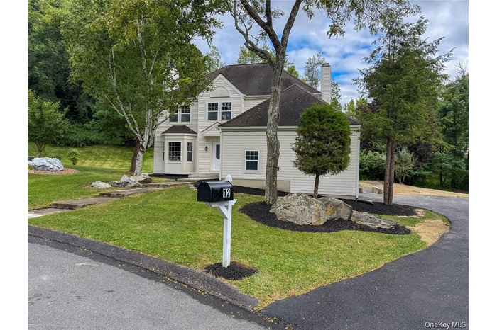 Traditional-style home with a front yard, a chimney, and a shingled roof