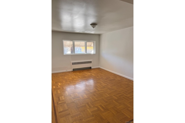 Unfurnished room featuring radiator and baseboards