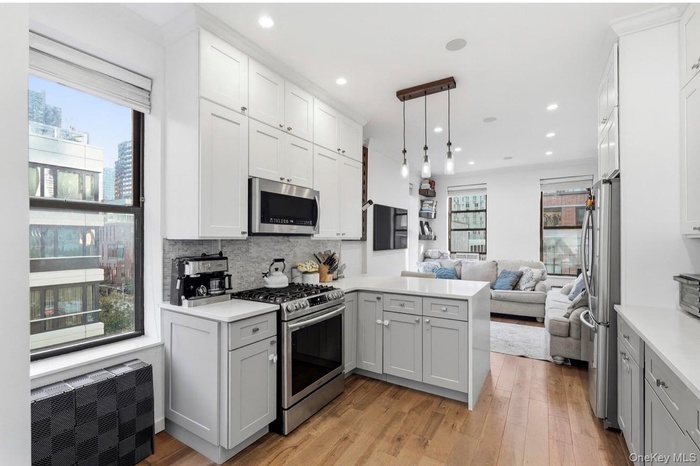 Kitchen featuring a peninsula, open floor plan, stainless steel appliances, light wood finished floors, and tasteful backsplash