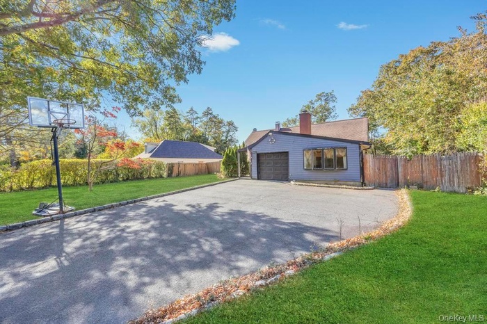 View of side of property featuring a chimney and asphalt driveway