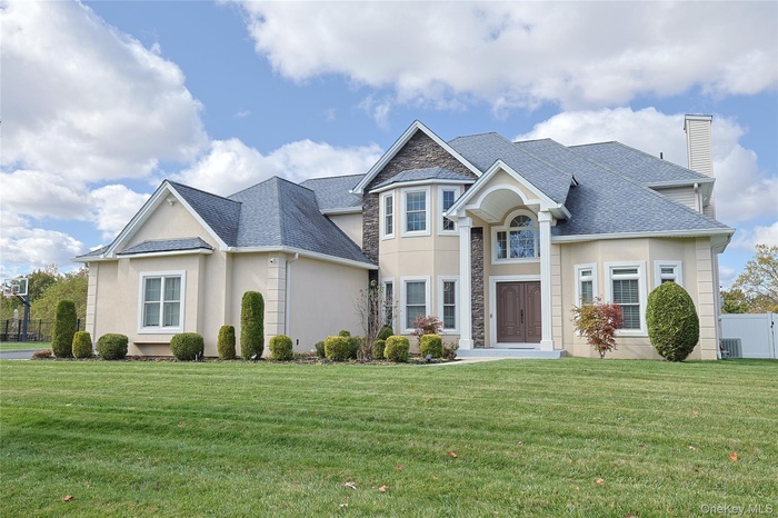 View of front of home with a chimney, stucco siding, a shingled roof, and stone siding