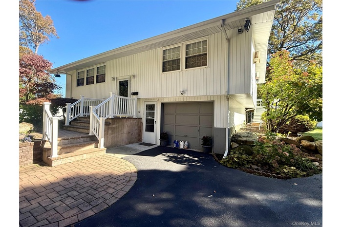 Bi-level home featuring driveway, an attached garage, and a patio area