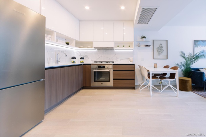 Kitchen with modern cabinets, open shelves, white cabinetry, stainless steel appliances, and backsplash