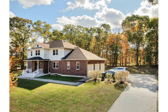 View of front of property featuring a front yard, covered porch, driveway, and brick siding