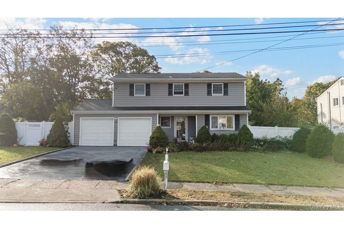 Traditional-style home featuring asphalt driveway, a garage, and a porch