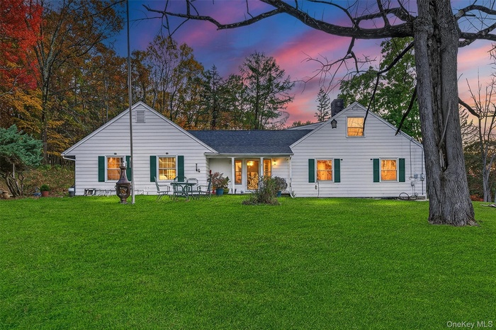 Rear view of property featuring a lawn, a chimney, a shingled roof, and a porch