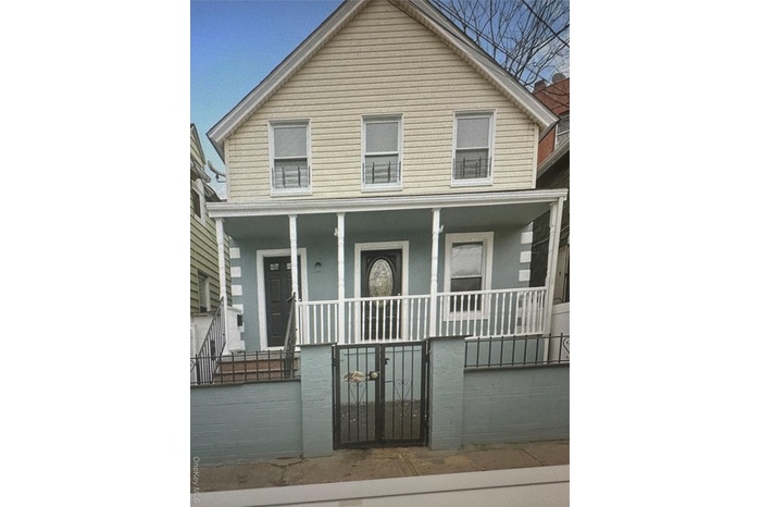 View of front of property featuring covered porch, a gate, and a fenced front yard