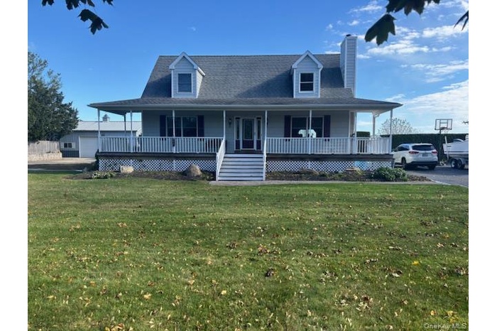 Country-style home with covered porch, a chimney, a front lawn, and roof with shingles