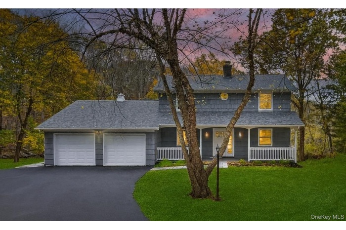 Traditional home with a chimney, a porch, a front yard, and an attached garage