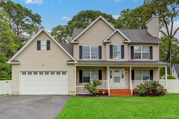 View of front of home with driveway, a chimney, a porch, and roof with shingles