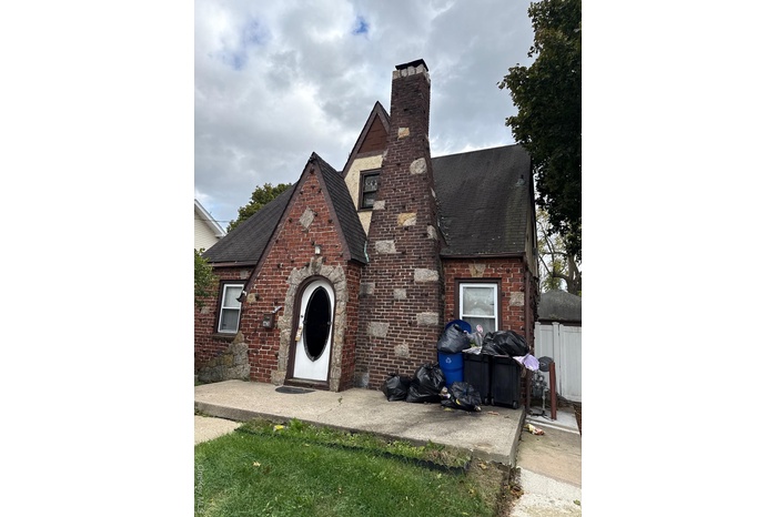 Tudor house with roof with shingles, a chimney, and brick siding