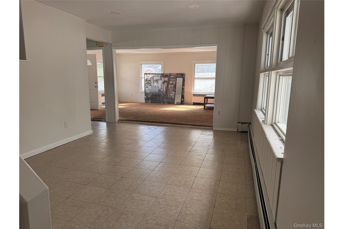 Empty room featuring a baseboard heating unit, radiator, and light tile patterned floors