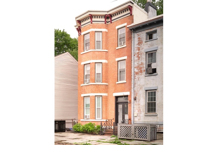 View of front of house featuring brick siding, a chimney, and cooling unit