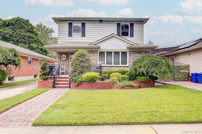View of front of house with stone siding, a front lawn, and covered porch