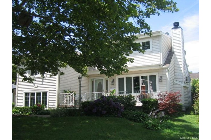 Rear view of house with a chimney and a lawn