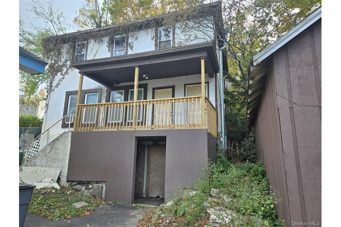 Rear view of house featuring stucco siding, a porch, and stairs