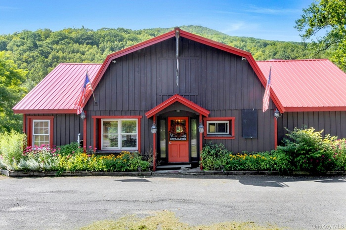 Chalet / cabin featuring a gambrel roof, a metal roof, and a view of trees