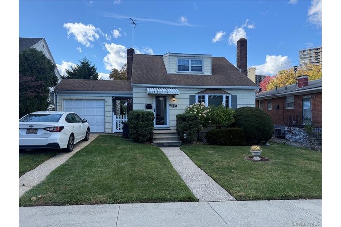 View of front of property with a chimney, a front yard, and roof with shingles