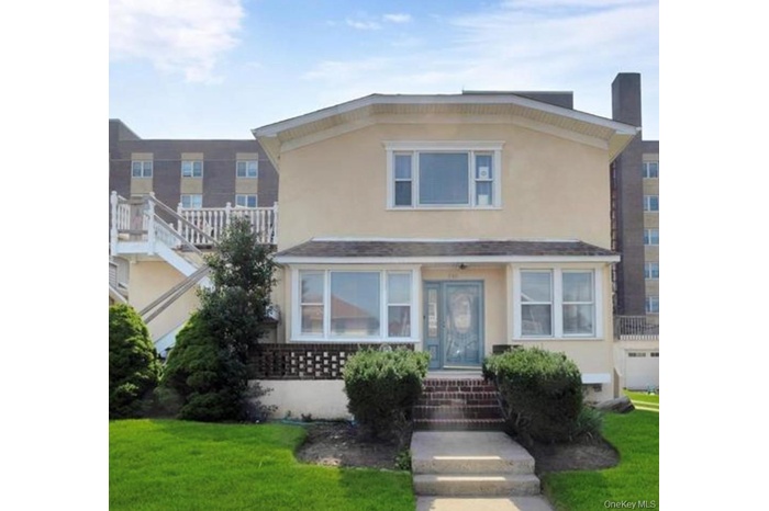 View of front of property with stucco siding, a front lawn, and a chimney