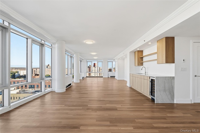 Hall with light wood finished floors, ornamental molding, and wine cooler