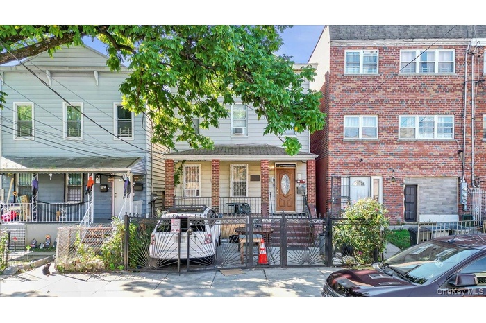 Traditional-style home featuring brick siding, a gate, a fenced front yard, and a porch