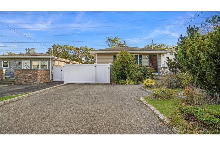 View of front of property with a gate, stone siding, and asphalt driveway