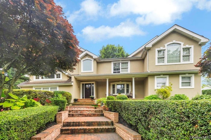 Traditional-style home featuring covered porch and stucco siding