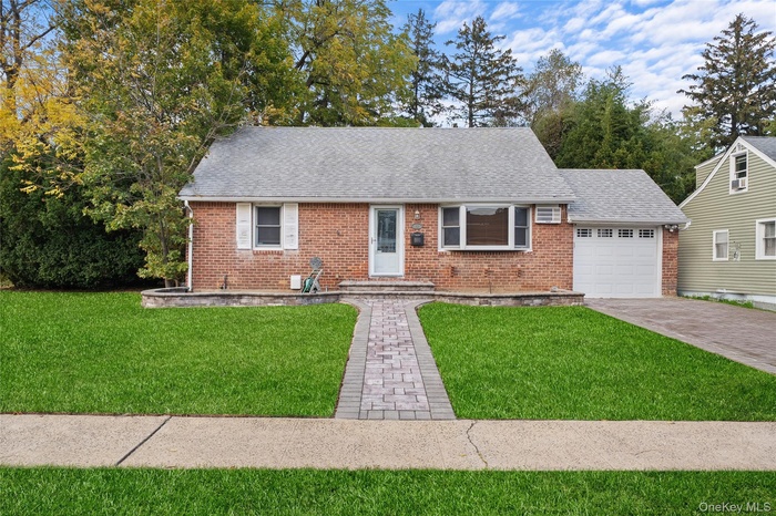 View of front of home with roof with shingles, a front lawn, a garage, and brick siding