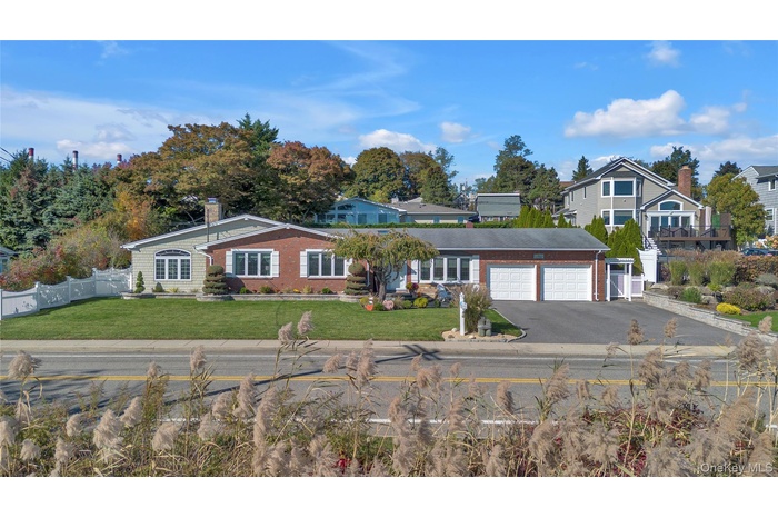 View of front of home featuring driveway, a chimney, brick siding, and an attached garage