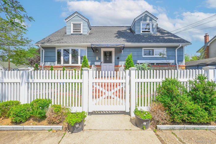 Cape cod house with a fenced front yard, a shingled roof, and a gate
