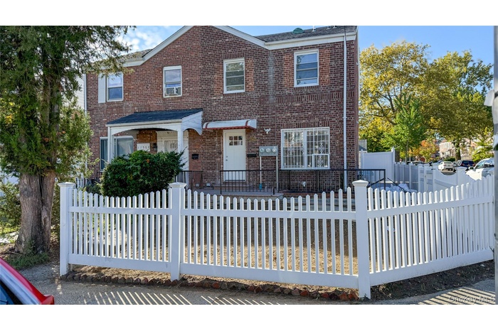 Traditional-style house featuring brick siding, a fenced front yard, and a deck