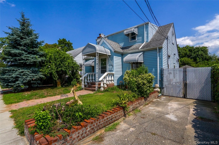 View of front of property with a gate, roof with shingles, and a chimney