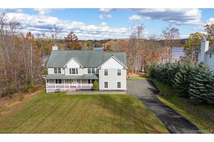 View of front of house with a porch, driveway, a chimney, and a front lawn