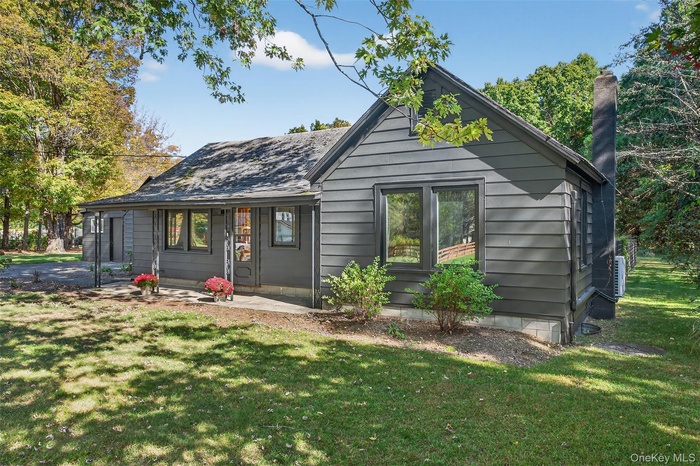 Back of property featuring a lawn and a chimney
