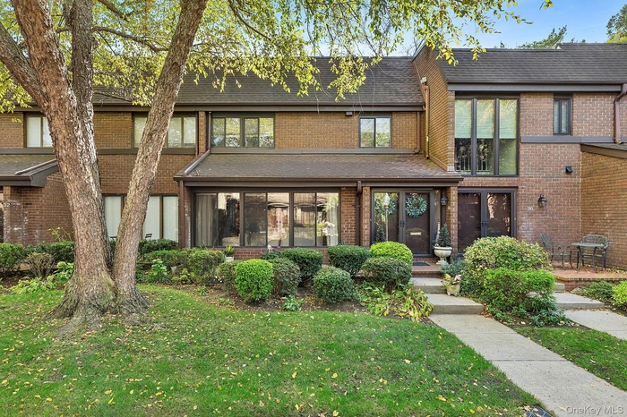 View of front of home with roof with shingles, a front yard, and brick siding