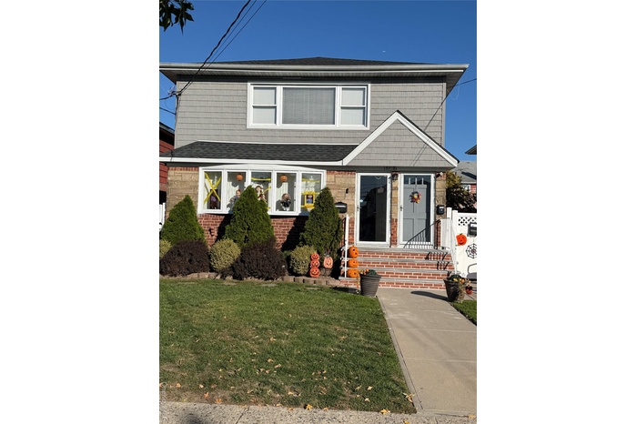 View of front facade with a front yard and a shingled roof