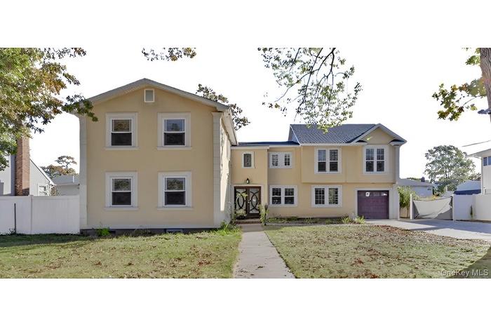 View of front facade featuring an attached garage, driveway, and stucco siding