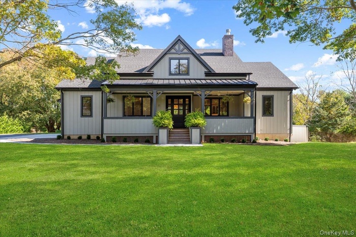 Rear view of property with a porch, roof with shingles, a yard, and board and batten siding