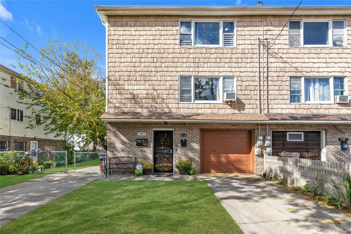 View of front of house featuring a gate, concrete driveway, and brick siding