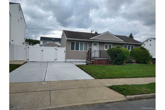 View of front facade featuring a gate, driveway, and roof with shingles