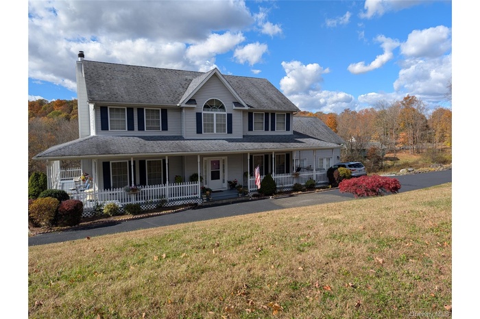 View of front of house with a porch, a front lawn, and a chimney